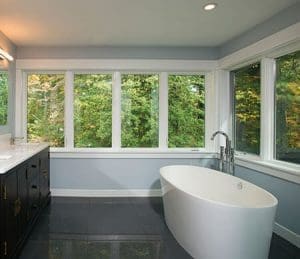 Modern bathroom with freestanding tub and windows.