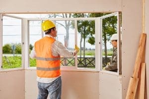 Two construction workers installing a new window.