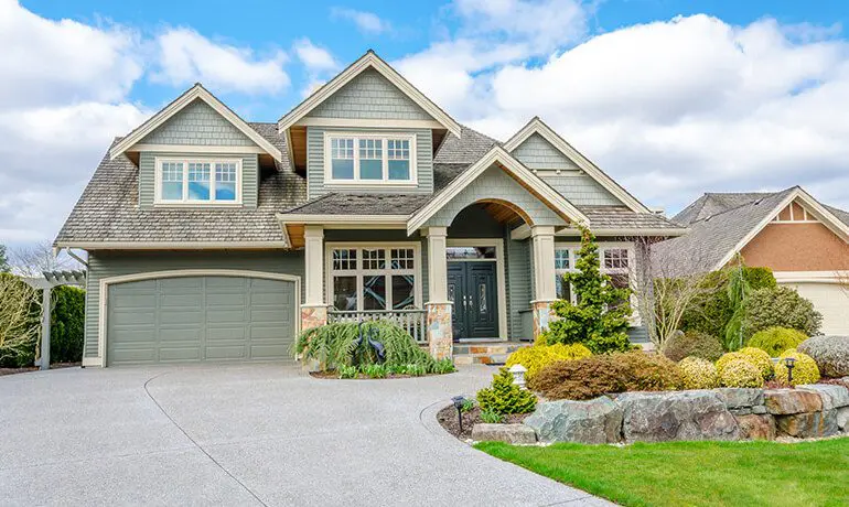 Green house with driveway and landscaping.