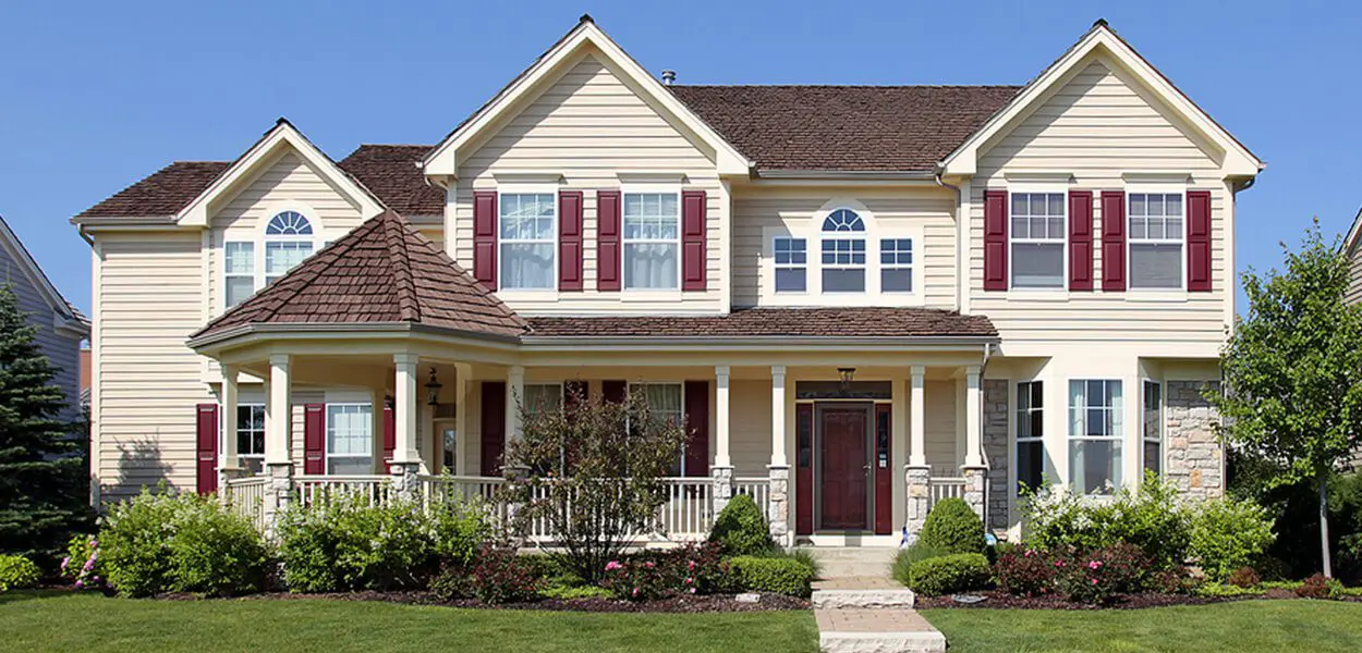 Beige house with red shutters and a porch.