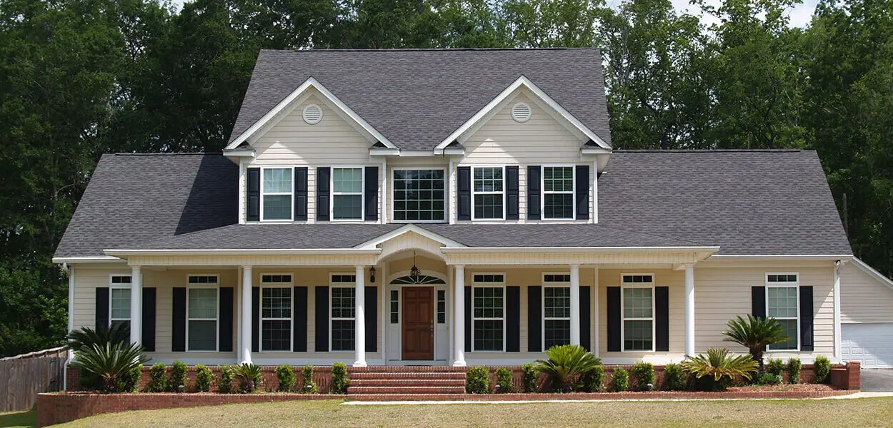 Beige house with black shutters and a porch.