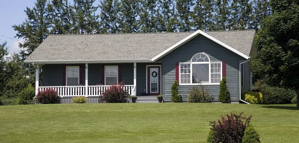 Gray house with a white porch and green lawn.