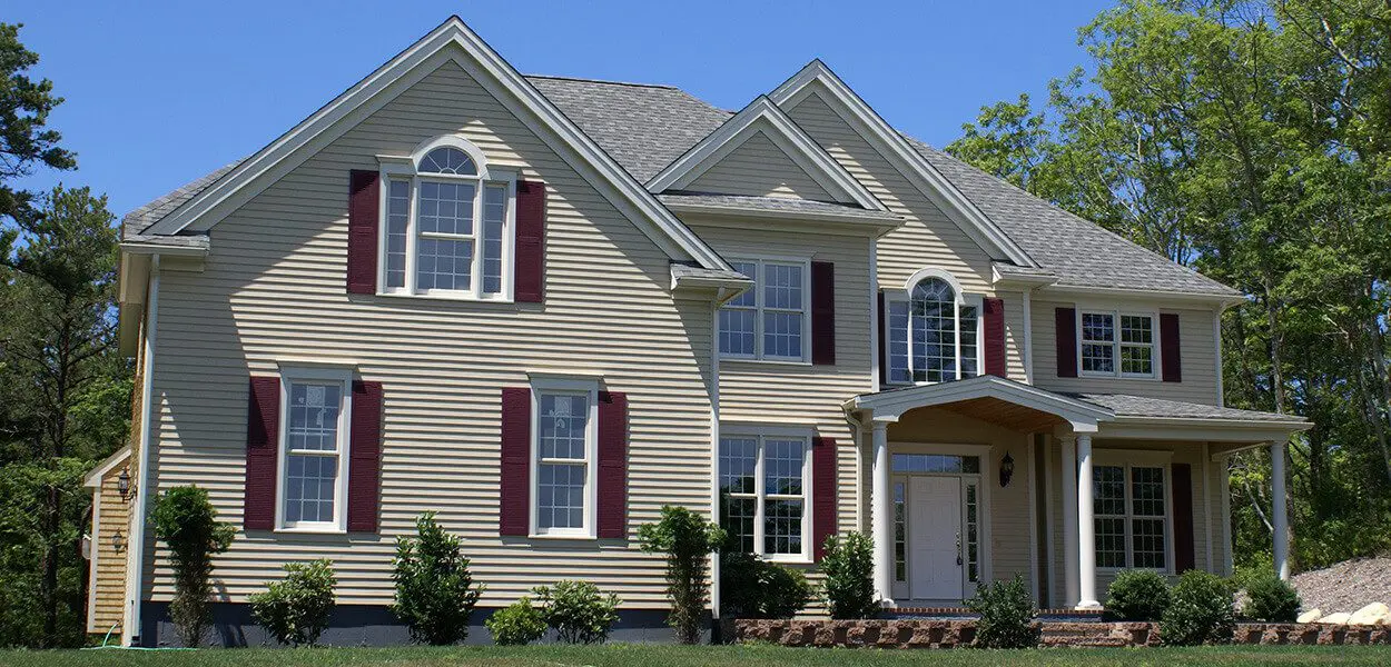 Beige suburban home with red shutters.