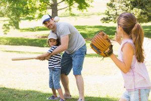 A family playing baseball in a park.